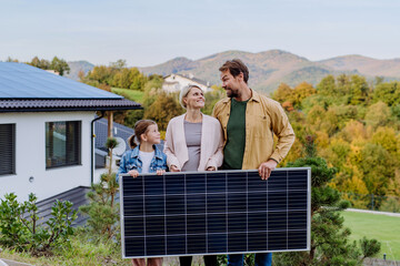 Happy family near their house with solar panel. Alternative energy, saving resources and sustainable lifestyle concept.