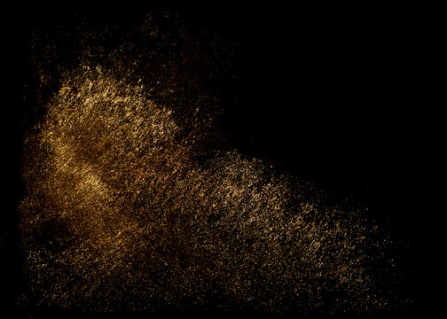 Golden sequins glisten with dust isolated on a black background. Horizontal abstract background with sparkling dust, space for text