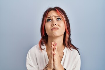 Young caucasian woman wearing casual white shirt over isolated background begging and praying with...