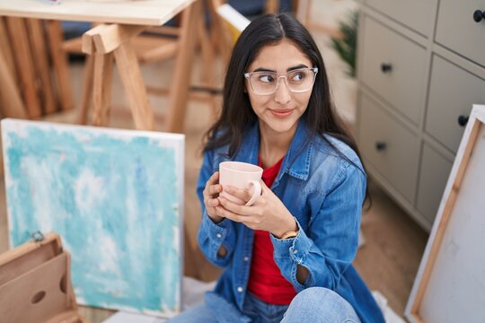 Young hispanic girl artist smiling confident drinking coffee at art studio
