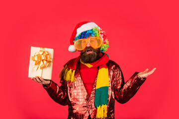 brutal man hold present box. winter holiday party. mature guy celebrate new year. bearded hipster in xmas party glasses. christmas online shopping. man with beard in santa claus hat. copy space