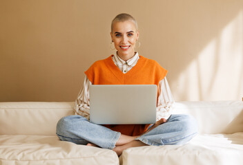 Beautiful woman freelancer with very short hair   working at laptop at home