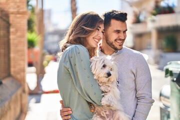 Man and woman holding dog hugging each other at street