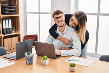 Obraz premium Young man and woman business workers hugging each other working at office