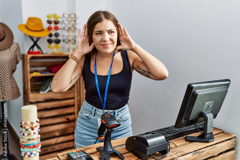 Canvas Prints young brunette woman holding banner with open text at retail shop trying to hear both hands on ear g