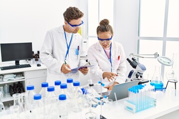 Fototapeta premium Man and woman wearing scientist uniform using laptop working at laboratory
