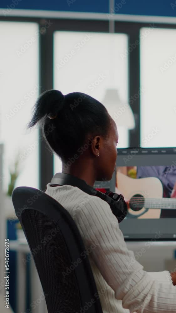 Poster african video editor looking at camera smiling editing video project in post production software wor