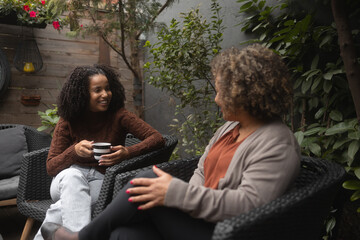 Fototapeta premium Shot of a young African-American woman bonding with her mother. They sit on the patio and have a coffee.