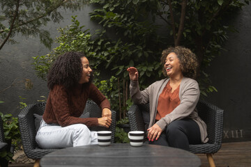 Shot of a young African-American woman bonding with her mother. They sit on the patio and have a coffee.