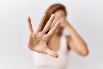 Middle age hispanic woman standing over isolated background covering eyes with hands and doing stop gesture with sad and fear expression. embarrassed and negative concept.