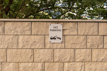 a rectangular plaque on the stone wall signifying a ban on parking vehicles. Signs regulating the...