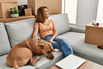 Young caucasian woman hugging dog sitting on sofa at home
