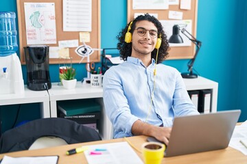 Young latin man business worker using laptop and headphones working at office