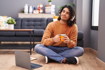 Young latin man listening to music drinking coffee at home