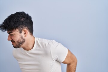 Hispanic man with beard standing over white background suffering of backache, touching back with hand, muscular pain