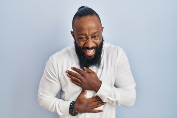 African american man standing over blue background smiling and laughing hard out loud because funny crazy joke with hands on body. - obrazy, fototapety, plakaty