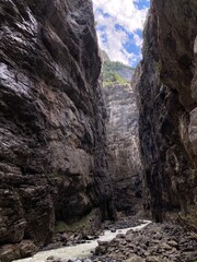 Rocky canyon in the Switzerland. Big rocks and boulders in the canyon. Summer day with blue sky canyon with green forest on the top. Huge canyon with river and waterfalls inside.
