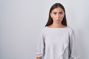 Young hispanic woman standing over white background depressed and worry for distress, crying angry...