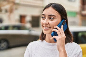 Young hispanic woman smiling confident talking on the smartphone at street