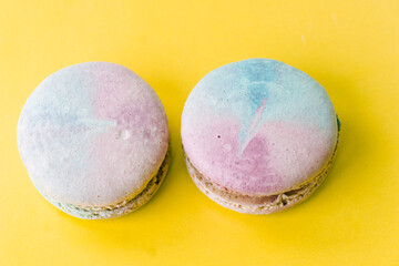 Tasty colorful macaroon. Two blue and pink macaroons on a yellow background. Most delicate cake is a cookie made of two smooth halves, fastened with fillings. French pastry made from egg whites.