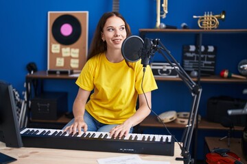 Young woman musician singing song playing piano keyboard at music studio