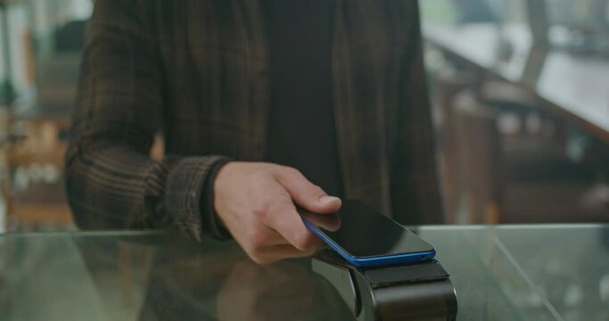 Young man customer paying order with cellphone wireless payment method. Male person using smartphone to pay product purchase