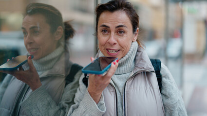 Middle age hispanic woman smiling confident talking on the smartphone at street