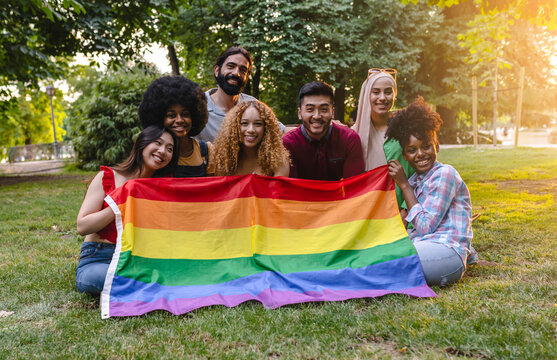 Multiracial group of lgbt people holding rainbow flag in park