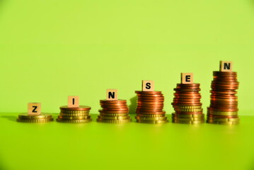 Das Wort Zinsen mit Holzwürfeln auf Geldhaufen