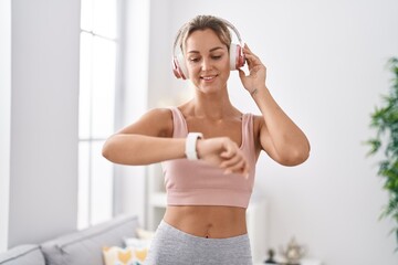 Young blonde woman listening to music using stopwatch at home