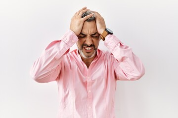 Middle age hispanic man standing over isolated background suffering from headache desperate and stressed because pain and migraine. hands on head.