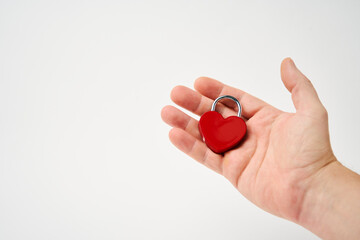Hand holding red heart shaped padlock on a white background