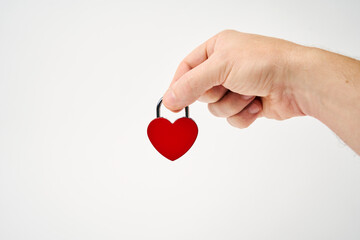 Hand holding red heart shaped padlock on a white background