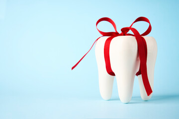White tooth model with red bow ribbon on a blue background