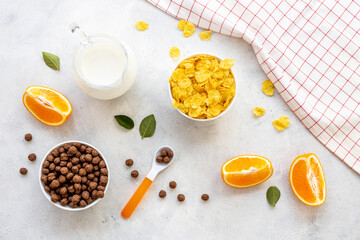 Kids breakfast with corn flakes, milk and orange, top view