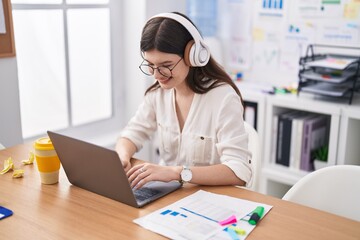 Young caucasian woman business worker using laptop and headphones working at office