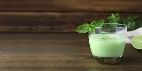 Delicious mint liqueur with green leaves on wooden table, space for text. Banner design