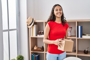 Young african american woman smiling confident holding package at home