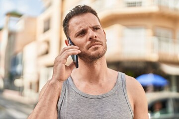 Young hispanic man talking on the smartphone with serious expression at street