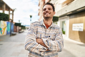 Young hispanic man smiling confident standing with arms crossed gesture at street