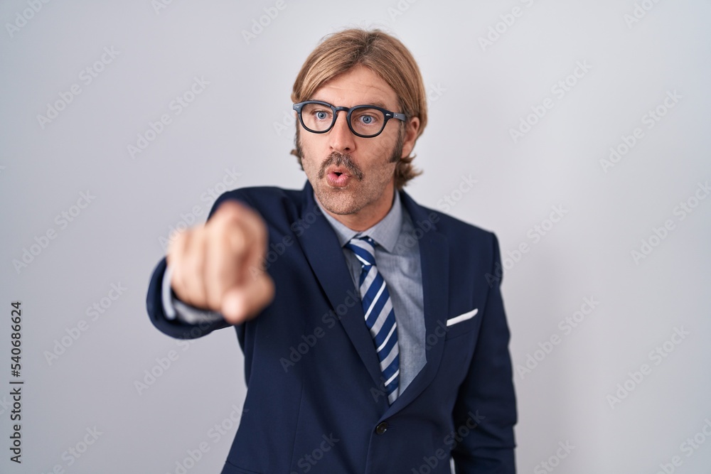 Poster caucasian man with mustache wearing business clothes pointing with finger surprised ahead, open mout