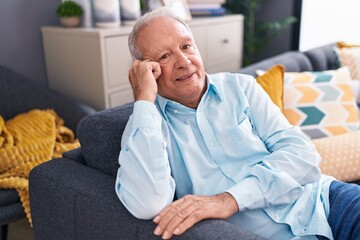 Fototapeta premium Middle age grey-haired man smiling confident sitting on sofa at home