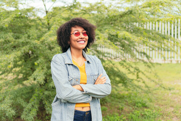 Portrait of a beautiful African American woman with sunglasses looking at the camera smiling. - Powered by Adobe