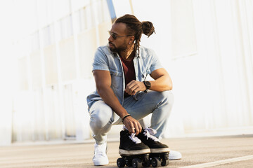 Black man enjoy outside. Modern man posing with roller skates.