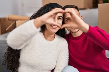 Man and woman couple doing heart gesture with hands at new home