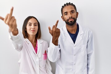 Young hispanic doctors standing over white background showing middle finger, impolite and rude fuck...