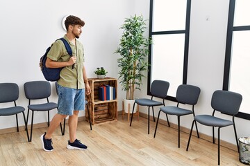 Young arab man wearing backpack standing at waiting room