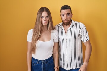 Young couple standing over yellow background depressed and worry for distress, crying angry and afraid. sad expression.