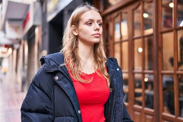Young blonde woman looking to the side with serious expression at street