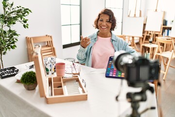 Middle age hispanic artist blogger smiling happy having video call at art studio.